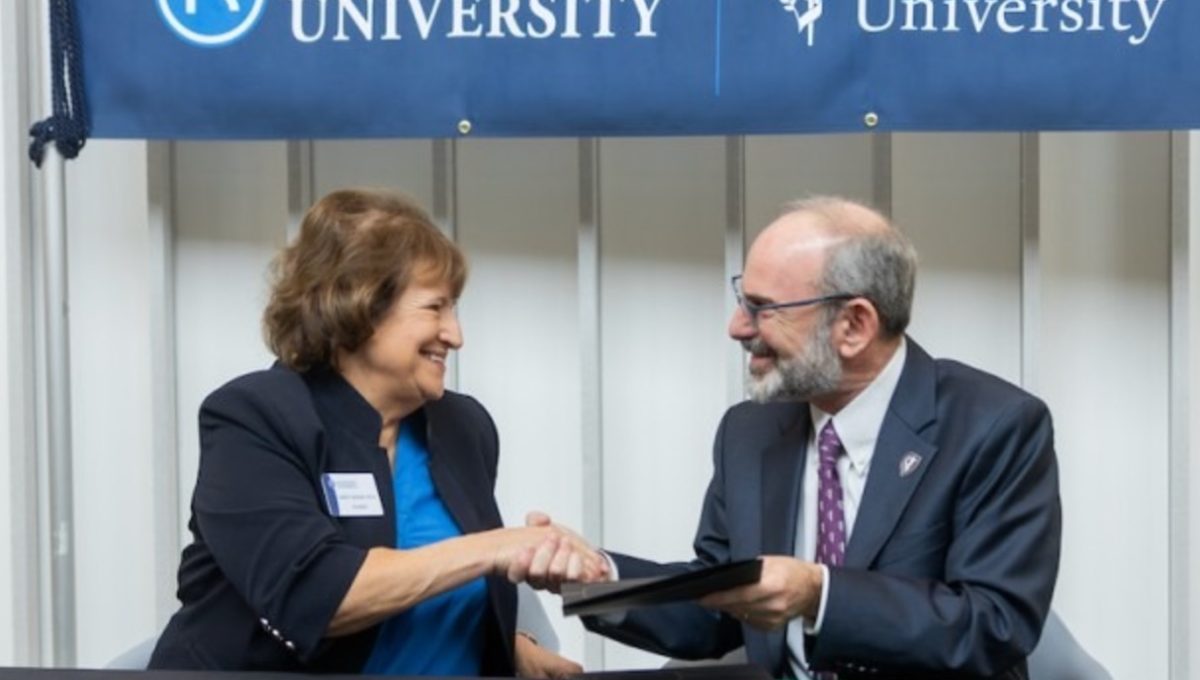 Rockhurst's President Sandra Cassady (left) and Kansas City University President and CEO Marc B. Hahn (right) shake hands on Friday, Nov. 8 to celebrate the Rockhurst University-Kansas City University Early Acceptance Program. Photo provided by Rockhurst Marketing.