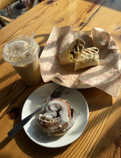 A spread of assorted items from Mildred's: iced coffee, wrap and cinnamon roll. 
